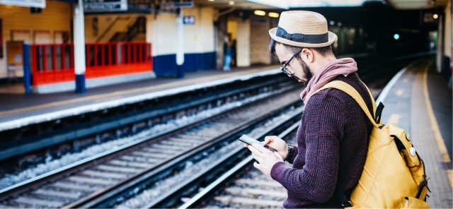Man standing at a railway station using his smartphone